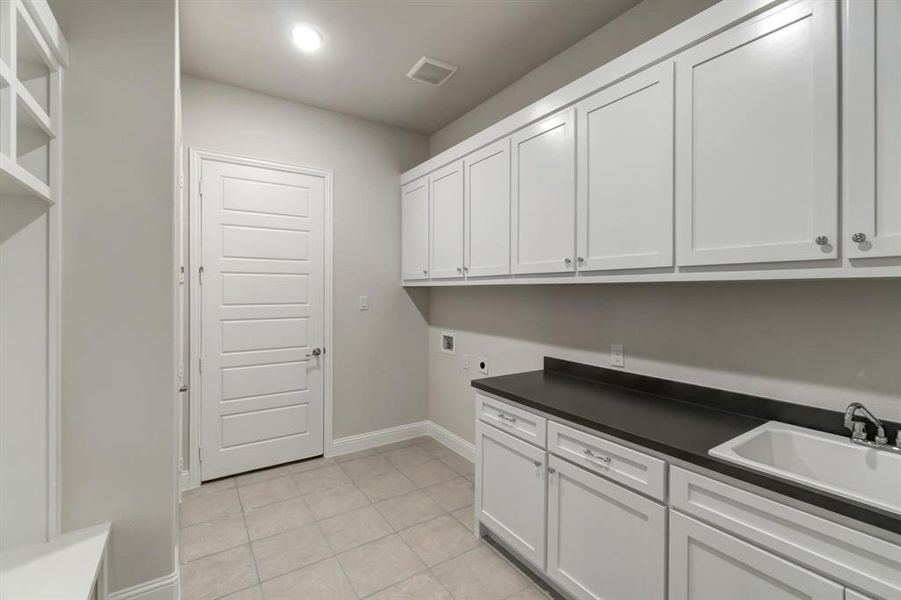 Washroom featuring light tile patterned flooring, hookup for an electric dryer, sink, and cabinets