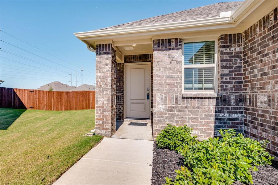 Property entrance featuring brick siding and a shingled roof Property entrance featuring brick siding and a shingled roof