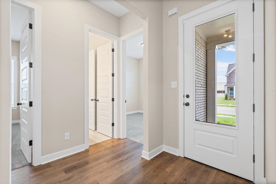 Entryway featuring wood-finish flooring, a full-lite front door, and neutral wall paint Entryway featuring wood-finish flooring, a full-lite front door, and neutral wall paint