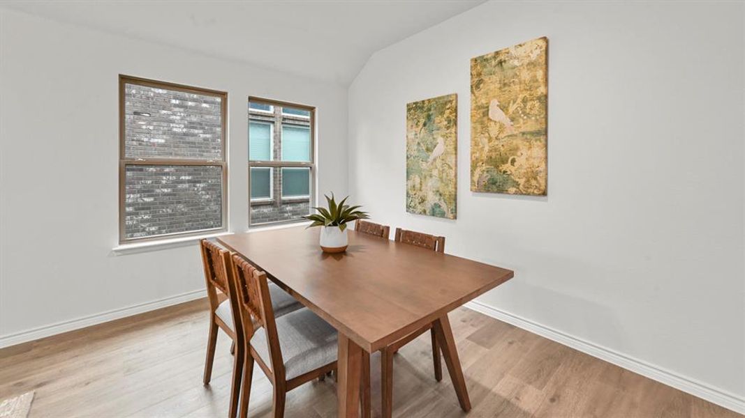 Dining space featuring vaulted ceiling and light wood finished floors