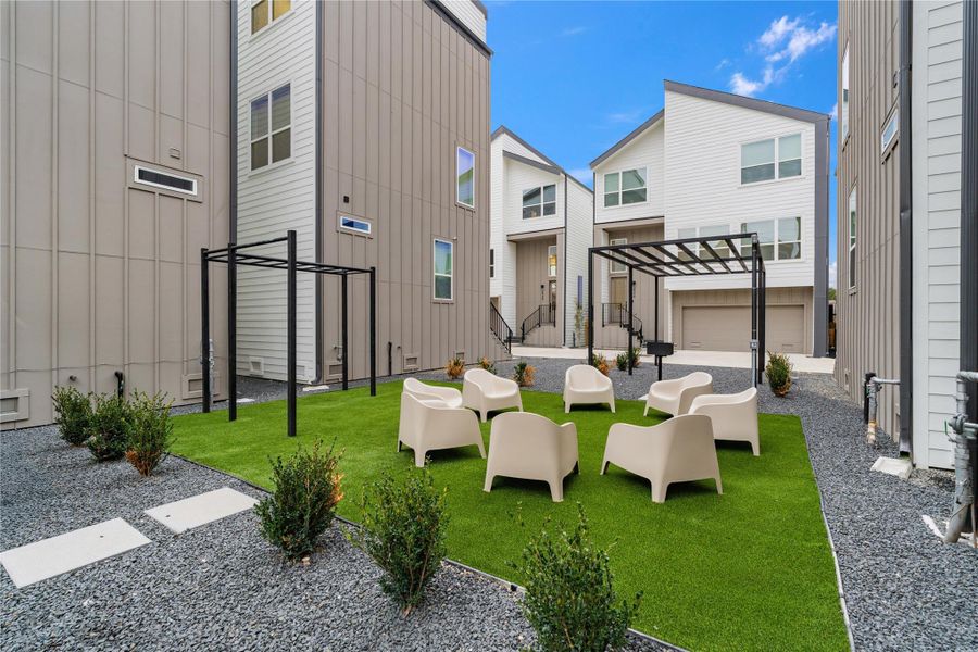 Designed for connection and ease, the central community courtyard offers a welcoming retreat with modern lounge seating, low-maintenance turf, and two sleek pergolas—ideal for grilling, gathering, or relaxing outdoors. Surrounded by contemporary homes, this shared green space balances privacy with a sense of neighborhood, creating a true extension of home.