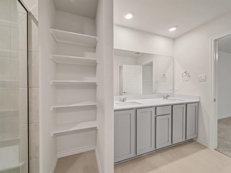 Bathroom featuring double vanity, a shower stall, baseboards, and a sink