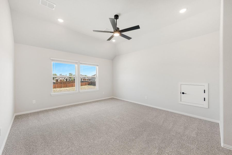 Empty bedroom with carpet, vaulted ceiling, black ceiling fan, and a window overlooking a backyard fence. Empty bedroom with carpet, vaulted ceiling, black ceiling fan, and a window overlooking a backyard fence.