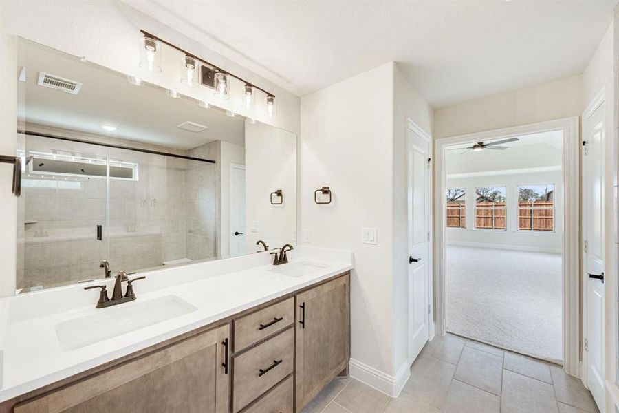 Bathroom featuring a stall shower, double vanity, light tile patterned flooring, and ceiling fan Bathroom featuring a stall shower, double vanity, light tile patterned flooring, and ceiling fan