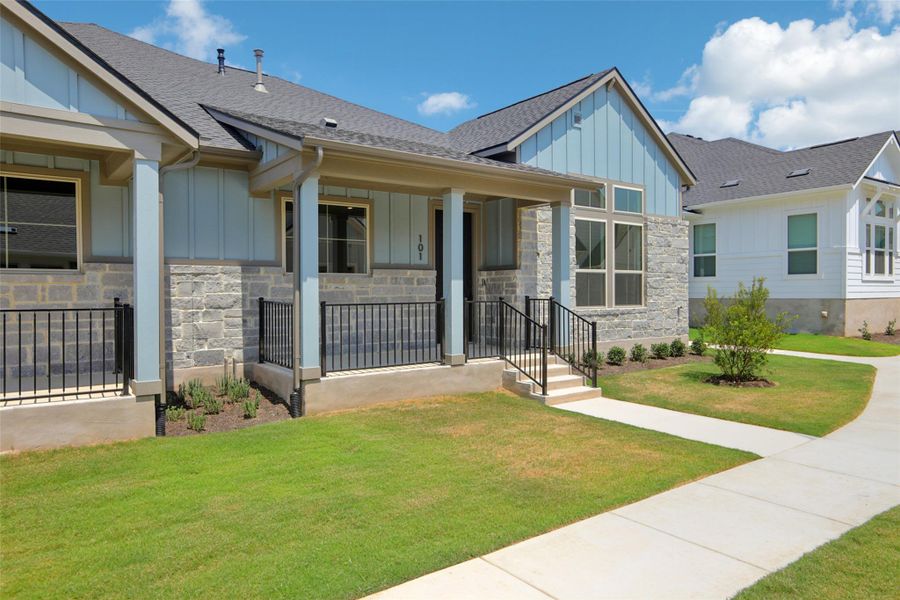 View of front of property with board and batten siding, stone siding, a porch, and a shingled roof