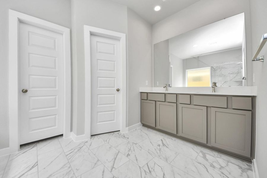 Elevate your daily routine at the elegant vanity, now equipped with double sinks, light countertops, modern hardware, and beautiful recessed lights.