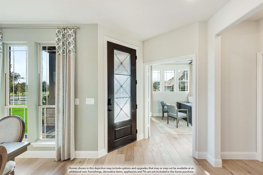 Entryway with dark wood front door, glass panel, hardwood floors, and view into home office