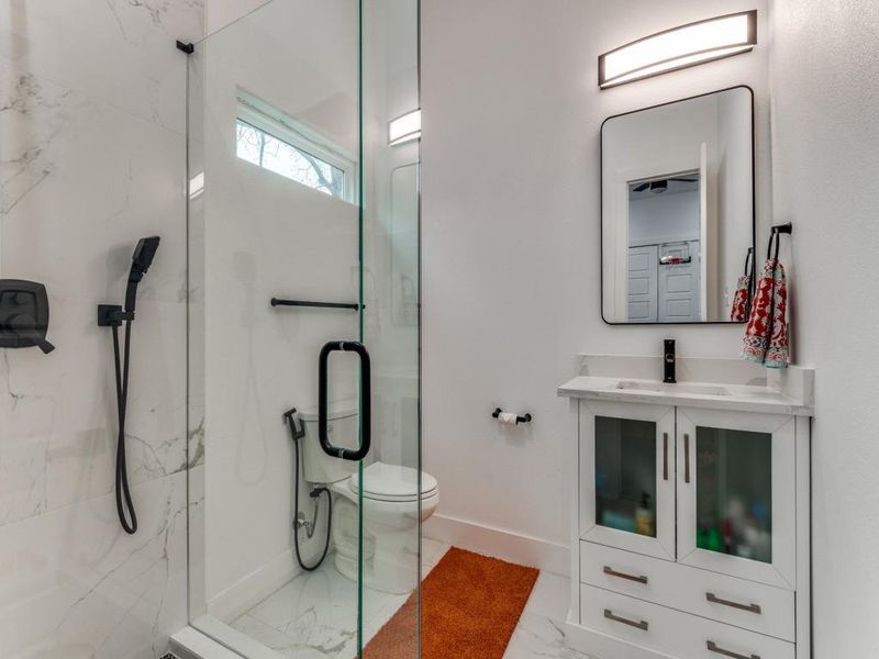 Full bathroom with vanity, a marble finish shower, and light marble finish flooring