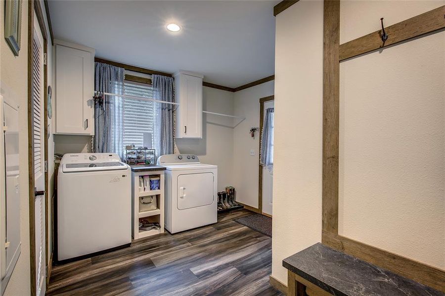 Utility room with LVP floors, storage closet, space for freezer or folding table, mud bench. Opens to side porch.