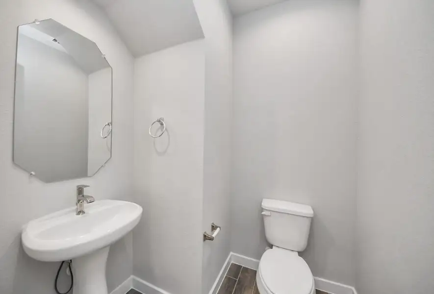 This half bathroom features a stylish pedestal sink, modern hardware, and bright recessed lighting, creating a sleek and inviting space. Sample photo of completed home with similar floor plan. Actual colors and selections may vary. This half bathroom features a stylish pedestal sink, modern hardware, and bright recessed lighting, creating a sleek and inviting space. Sample photo of completed home with similar floor plan. Actual colors and selections may vary.