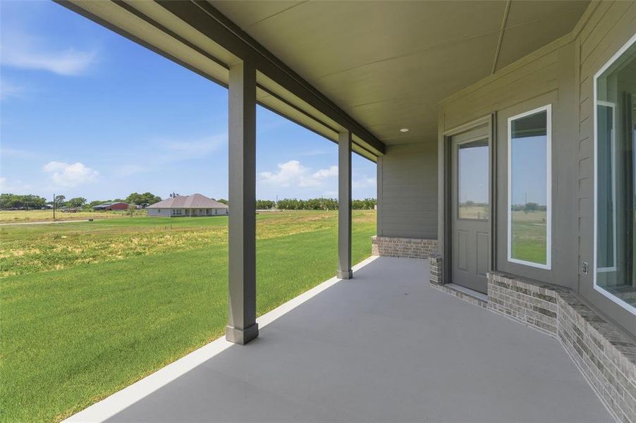 Covered patio featuring a concrete surface, gray siding, and a partial brick facade