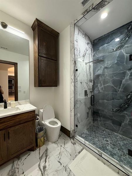 Full bath with light marble finish floors, a marble finish shower, and vanity