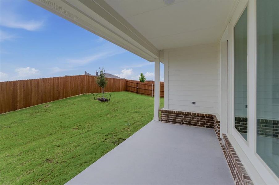 Covered patio with a concrete surface, featuring white siding, brick accents, and a ceiling-mounted light fixture