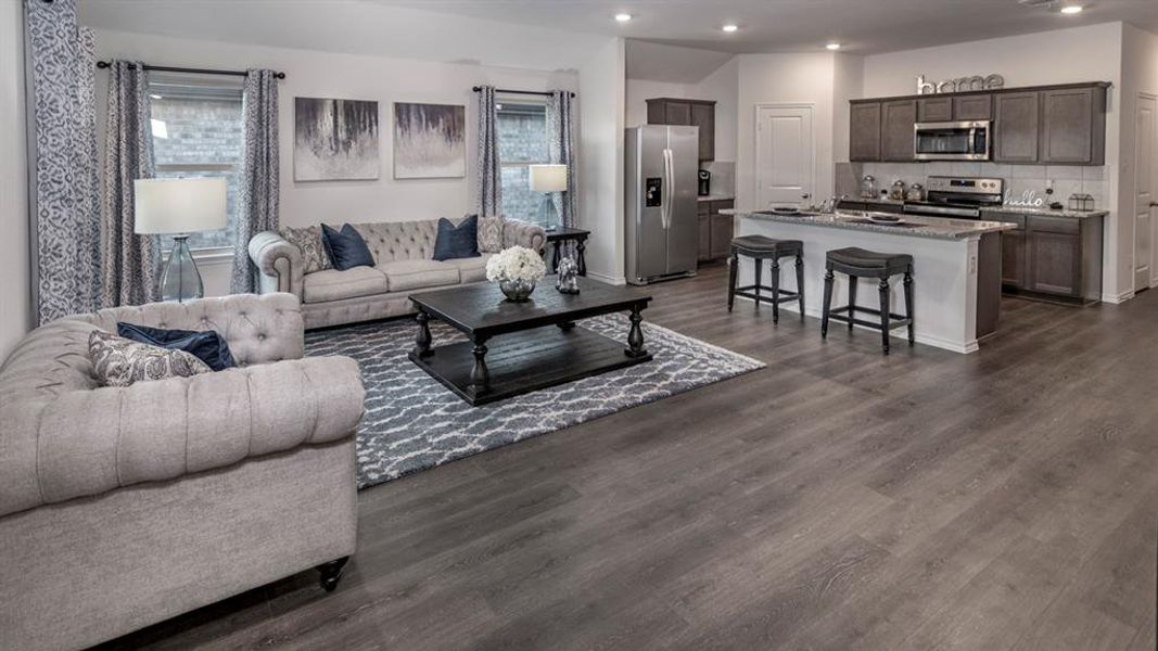 Living area featuring dark wood-style flooring, plenty of natural light, and recessed lighting