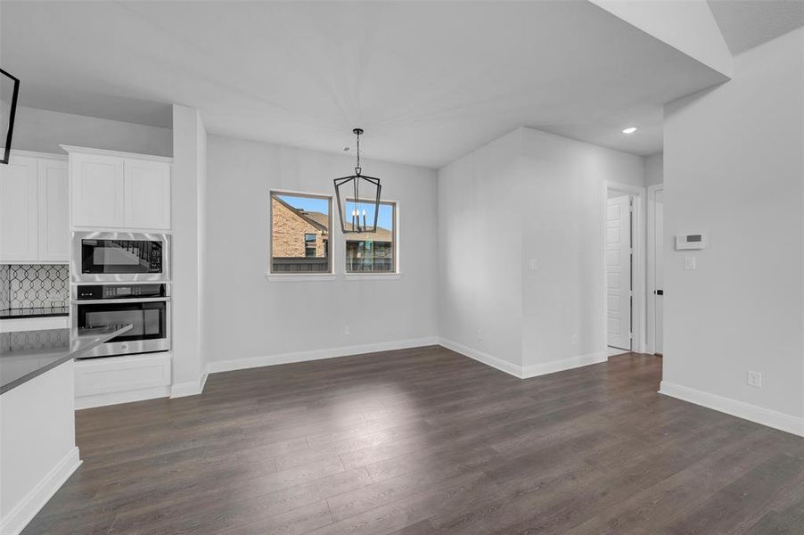 Unfurnished dining area with dark wood finished floors and a chandelier Unfurnished dining area with dark wood finished floors and a chandelier
