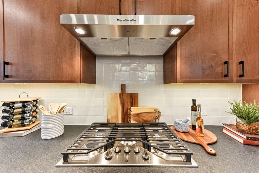 A sleek gas cooktop with a range hood anchors this modern kitchen's design. A sleek gas cooktop with a range hood anchors this modern kitchen's design.