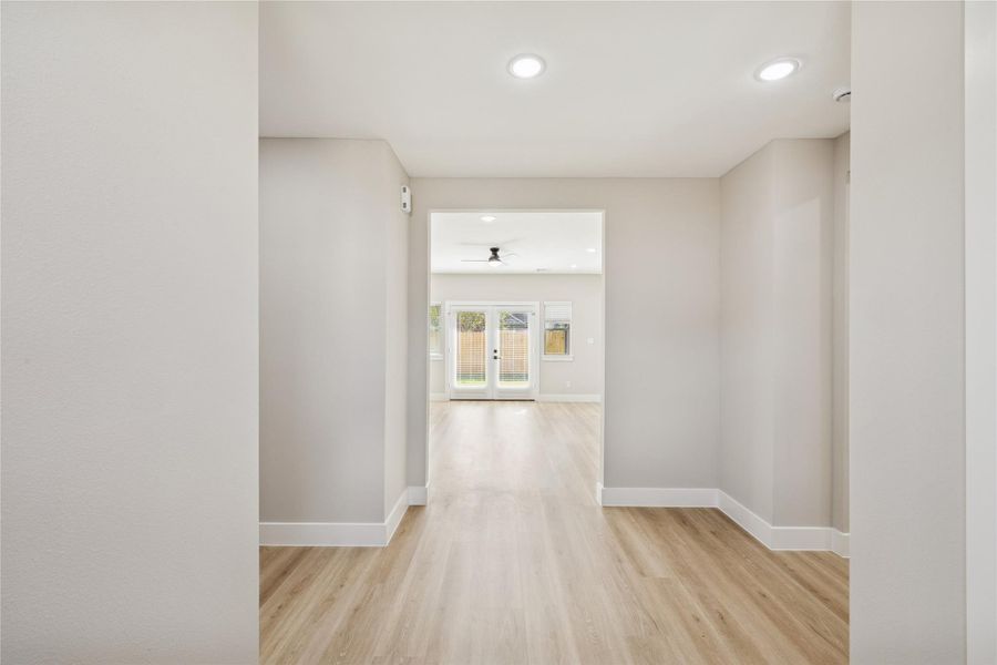 Welcome to an inviting entryway featuring sleek hardwood floors and abundant natural light, seamlessly leading to the heart of the home.