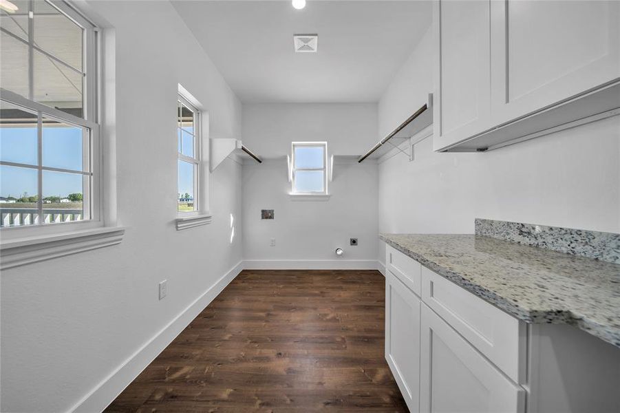 Laundry room featuring baseboards, dark wood-type flooring, hookup for an electric dryer, cabinet space, and hookup for a washing machine