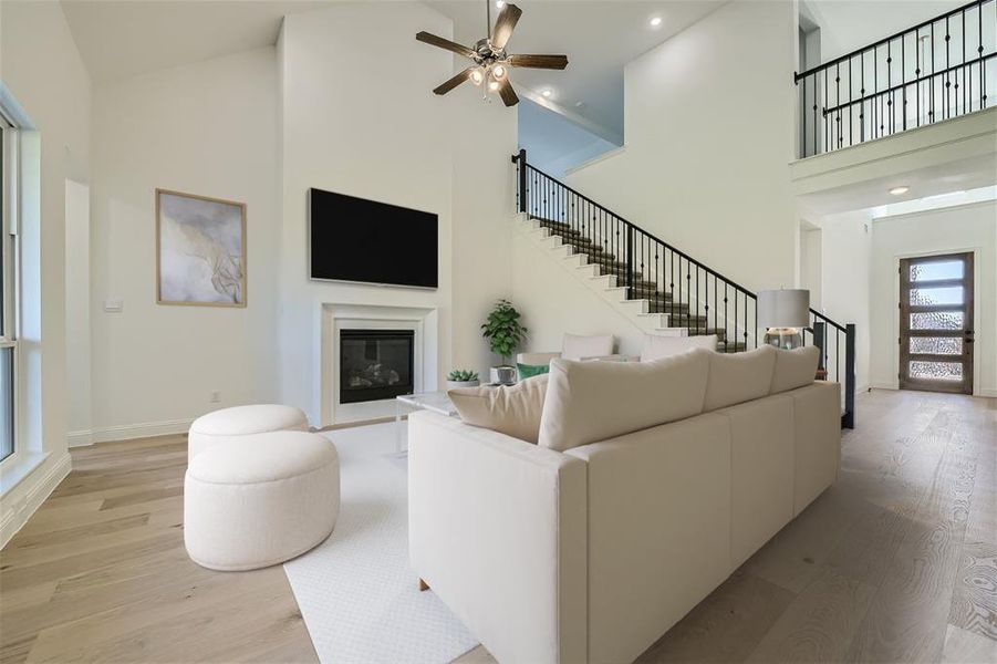 Living room featuring a towering ceiling, ceiling fan, and hardwood / wood-style flooring