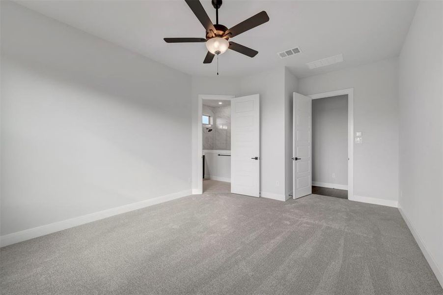 Unfurnished bedroom with carpet, a ceiling fan, and ensuite bath Unfurnished bedroom with carpet, a ceiling fan, and ensuite bath