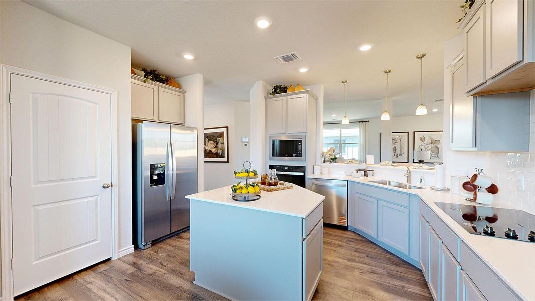 Kitchen with black appliances, a center island, light wood-style floors, and decorative light fixtures Kitchen with black appliances, a center island, light wood-style floors, and decorative light fixtures