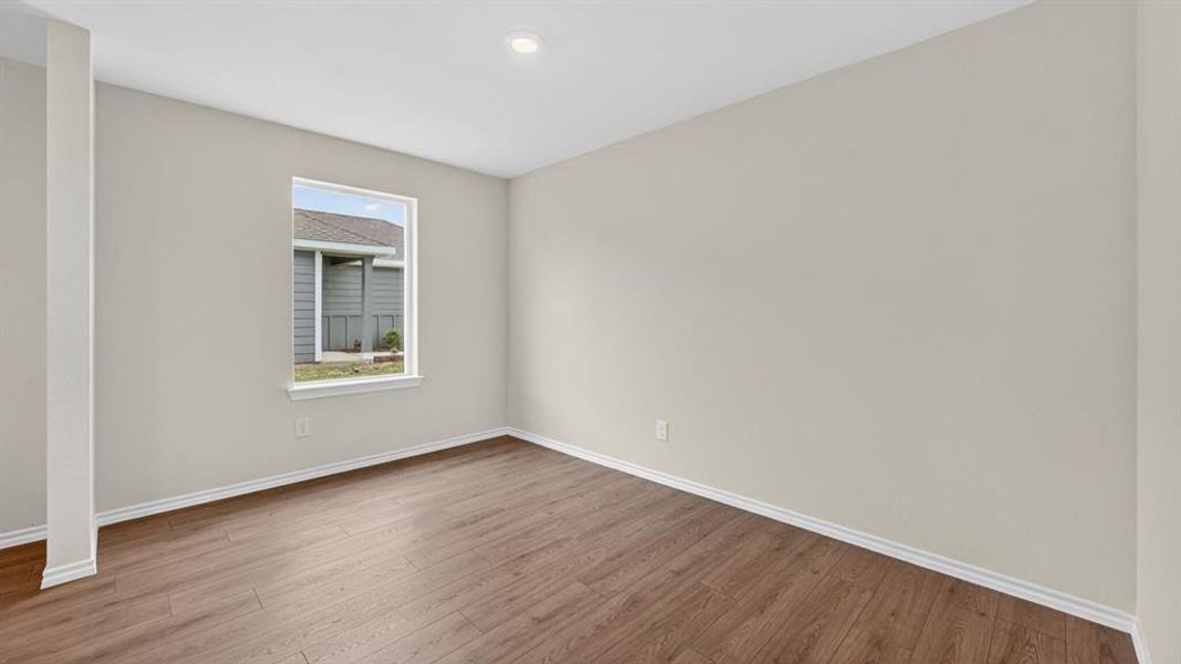 Neutral-toned interior featuring wood-finish flooring, a single window, and a recessed ceiling light