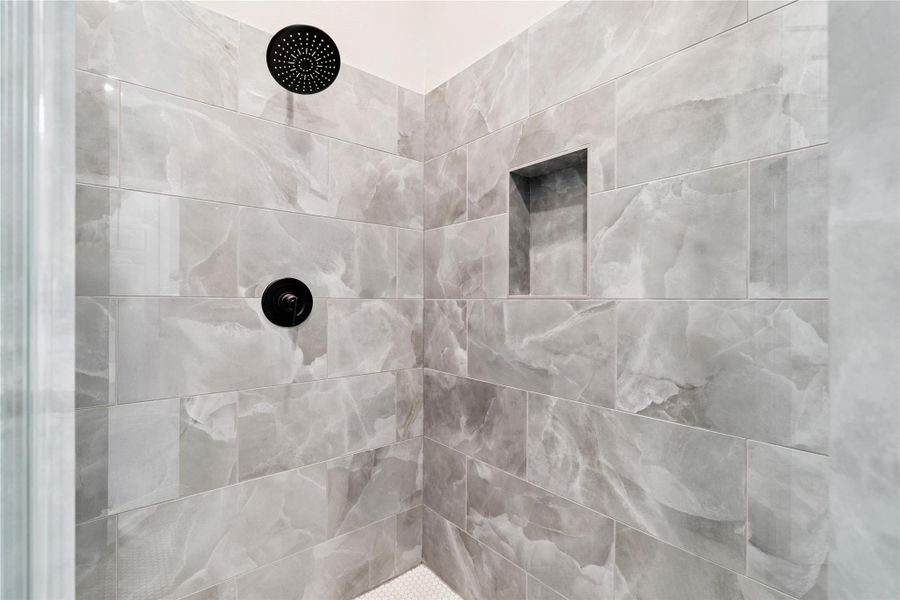 Large format tile and matte black hardware ground this walk-in shower with spa-level restraint.