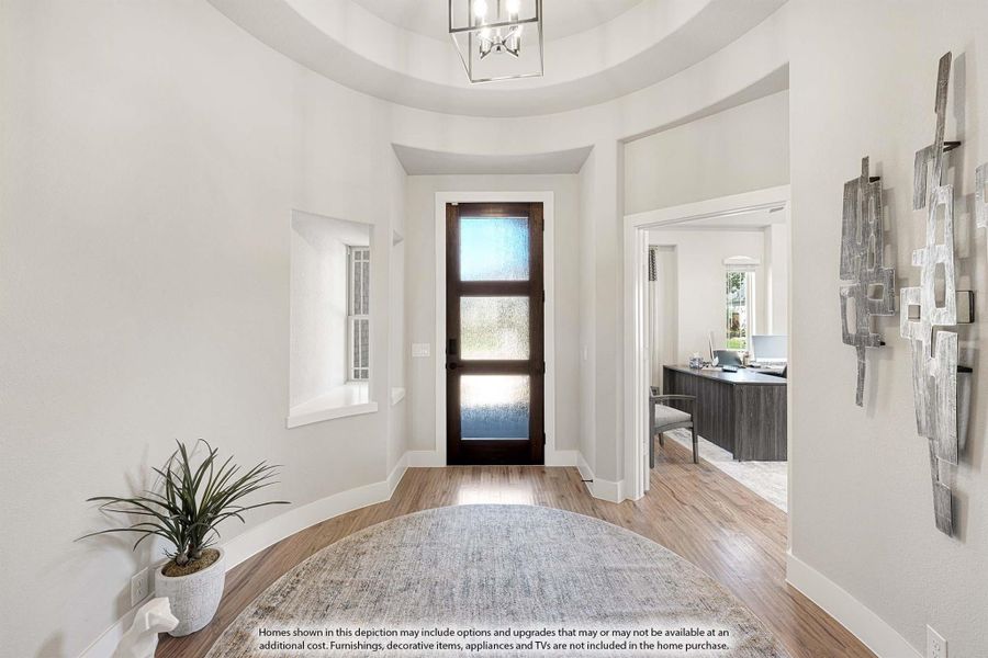 Foyer with round tray ceiling, dark wood glass-panel front door, chandelier, and hardwood floors leading to a home office.