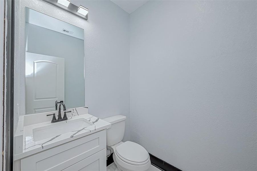 His half bathroom features a sleek quartz countertop.