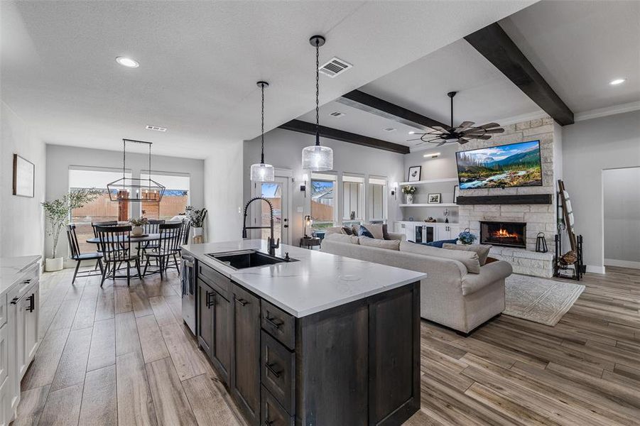 Kitchen featuring sink, light hardwood / wood-style flooring, white cabinets, a center island with sink, and decorative light fixtures