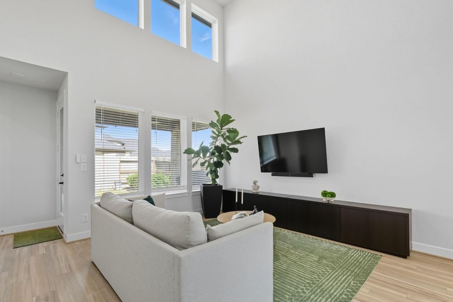 This amazing family room features a vaulted double height ceiling & an abundance of natural light through the windows looking out to the back patio.
