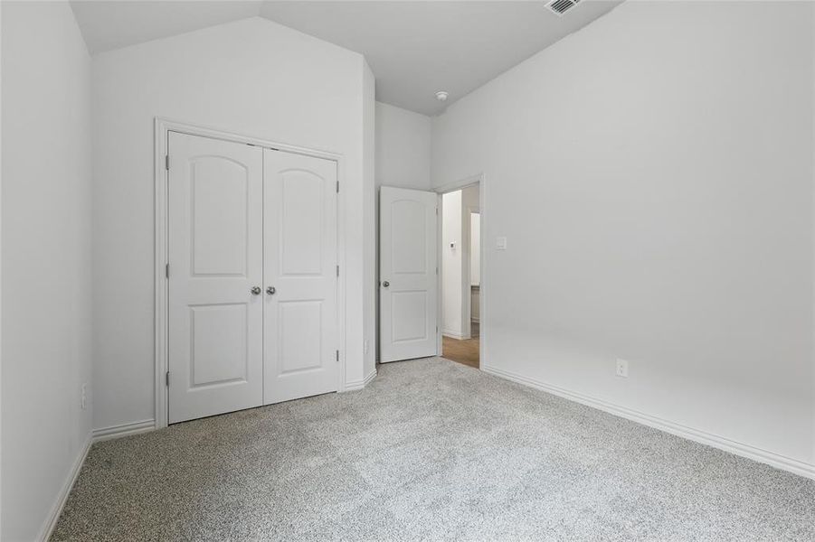 Unfurnished bedroom with light carpet, a closet, and vaulted ceiling
