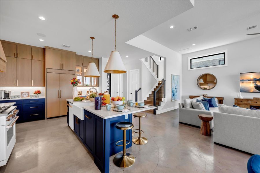 Open-concept living space featuring a gourmet kitchen, concrete flooring, and a contemporary staircase