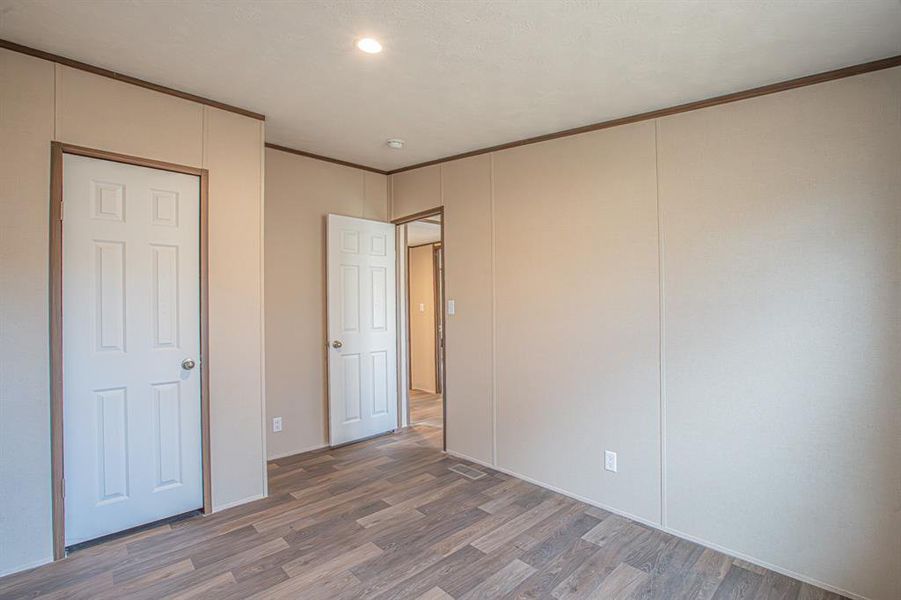 Unfurnished bedroom with wood-type flooring and crown molding Unfurnished bedroom with wood-type flooring and crown molding