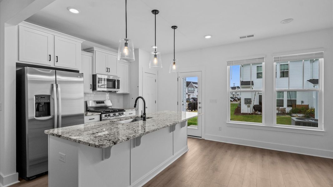 Tasteful design meets functional luxury in this kitchen with a 9-foot island and modern pendant lighting Tasteful design meets functional luxury in this kitchen with a 9-foot island and modern pendant lighting