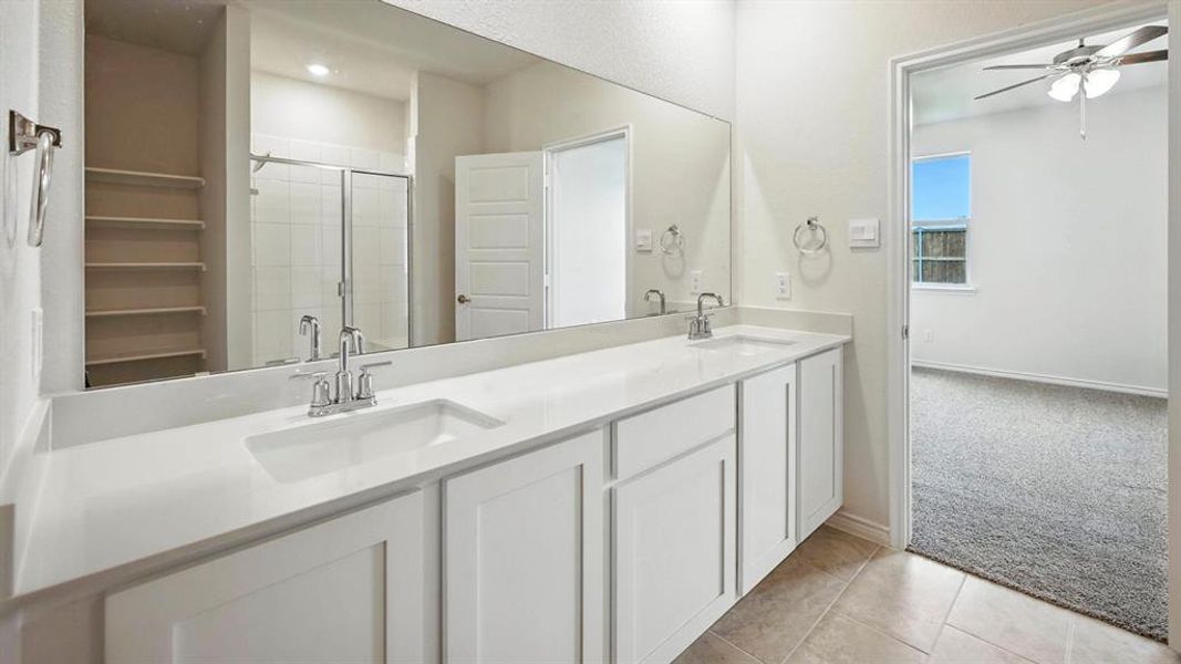 Bathroom featuring a dual-sink vanity with white cabinetry, a light-colored countertop, and a large wall-mounted mirror