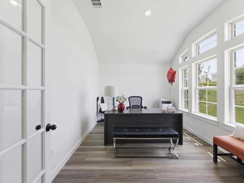 Bright room featuring a vaulted ceiling with recessed lighting, wood-finish flooring, and multiple large windows Bright room featuring a vaulted ceiling with recessed lighting, wood-finish flooring, and multiple large windows