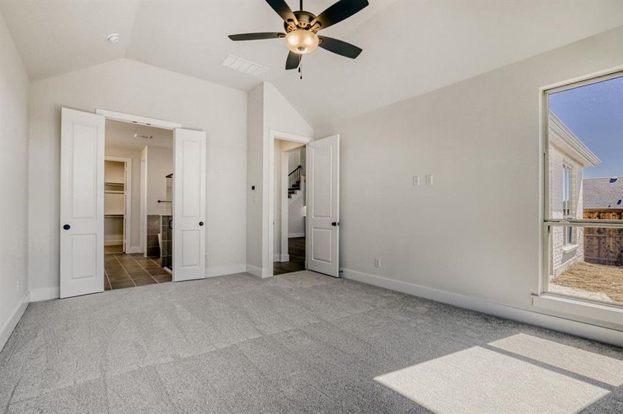 Unfurnished bedroom with carpet, lofted ceiling, ceiling fan, and ensuite bath