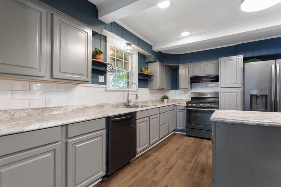 Kitchen featuring dishwasher, gas range oven, a sink, gray cabinetry, and stainless steel fridge