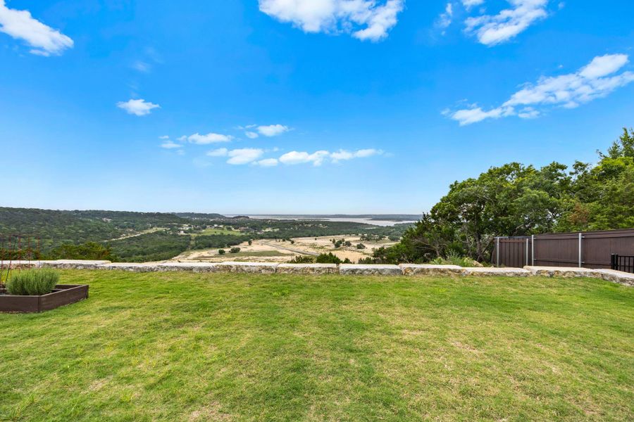 A tranquil panorama of hills and a distant lake, framed by a manicured lawn and a low stone wall. A tranquil panorama of hills and a distant lake, framed by a manicured lawn and a low stone wall.