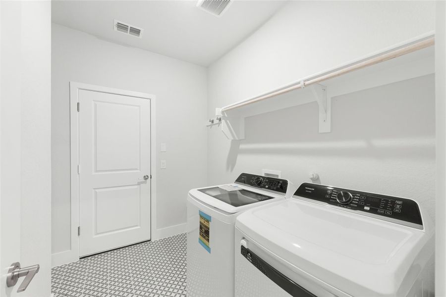 Laundry room with top-load washer and dryer, wall shelf, and patterned tile floor
