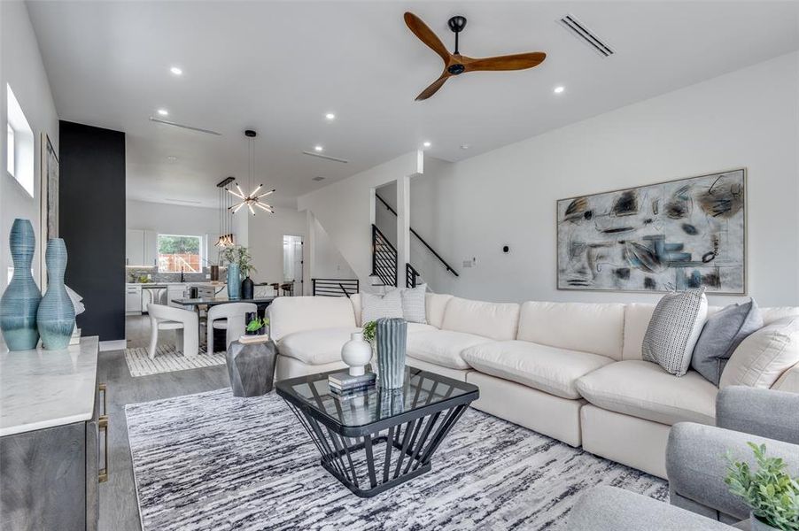 Living room with ceiling fan with notable chandelier and hardwood / wood-style floors