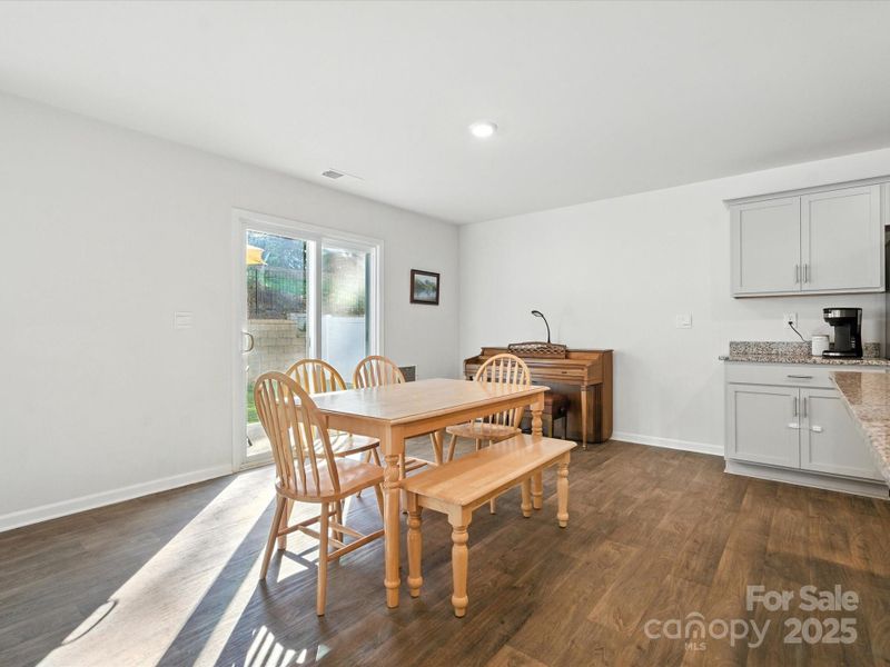 Spacious dining room overlooks private backyard through large sliding glass doors. Wood-look flooring and neutral walls provide flexible space that connects indoor and outdoor living areas.