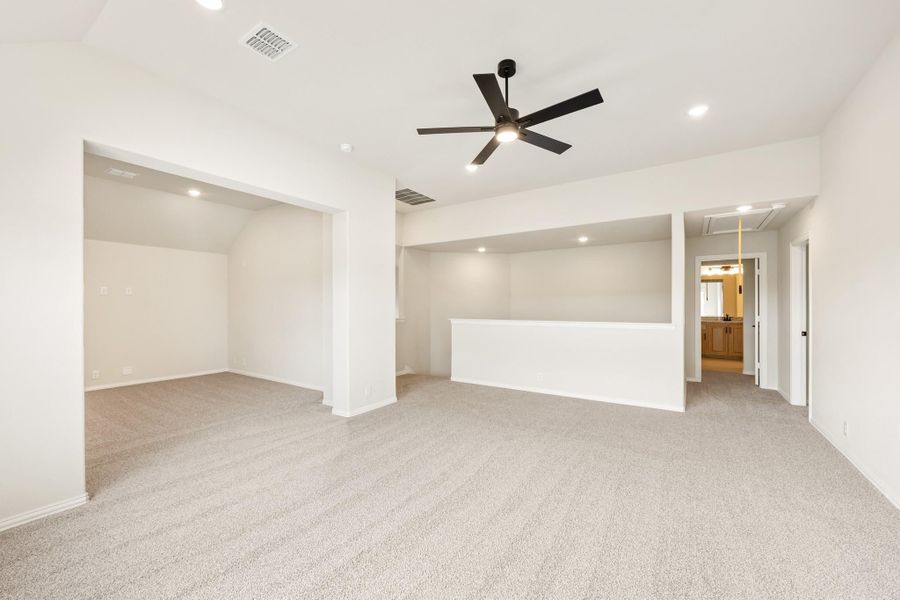 Spacious empty room with carpet flooring, ceiling fan, recessed lighting, and open doorways to adjacent rooms Spacious empty room with carpet flooring, ceiling fan, recessed lighting, and open doorways to adjacent rooms