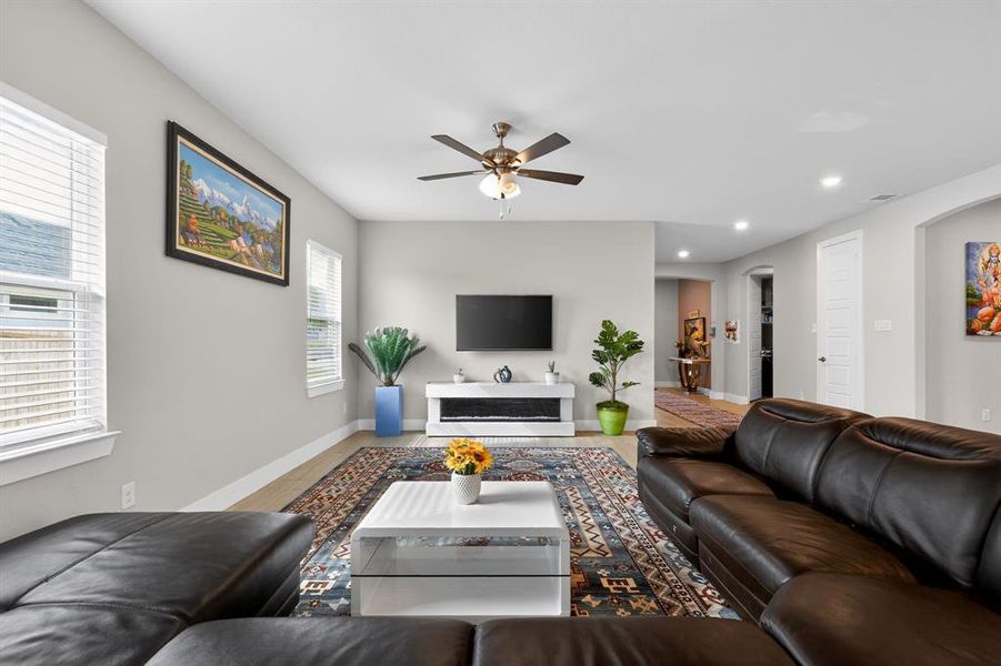Spacious living area featuring light-toned walls, recessed lighting, and a ceiling fan