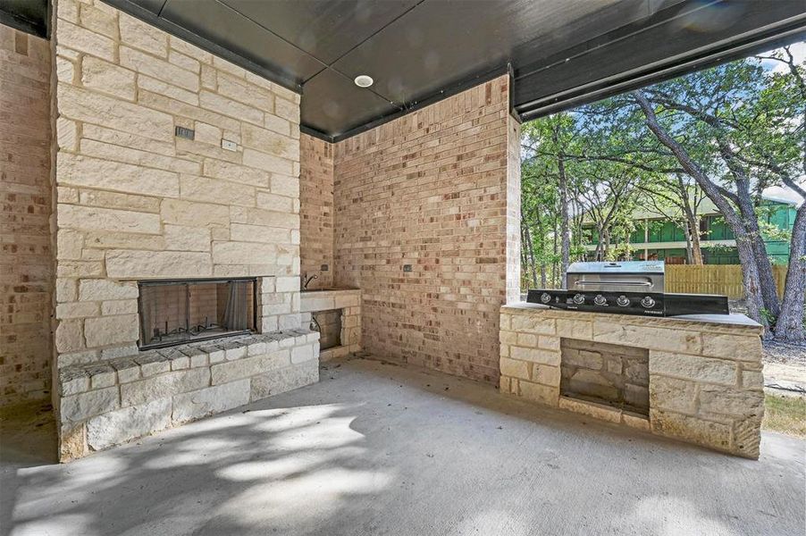 View of patio with an outdoor stone fireplace