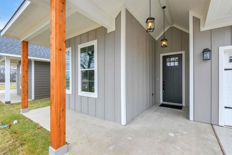 Entrance to property with covered porch, a shingled roof, and board and batten siding