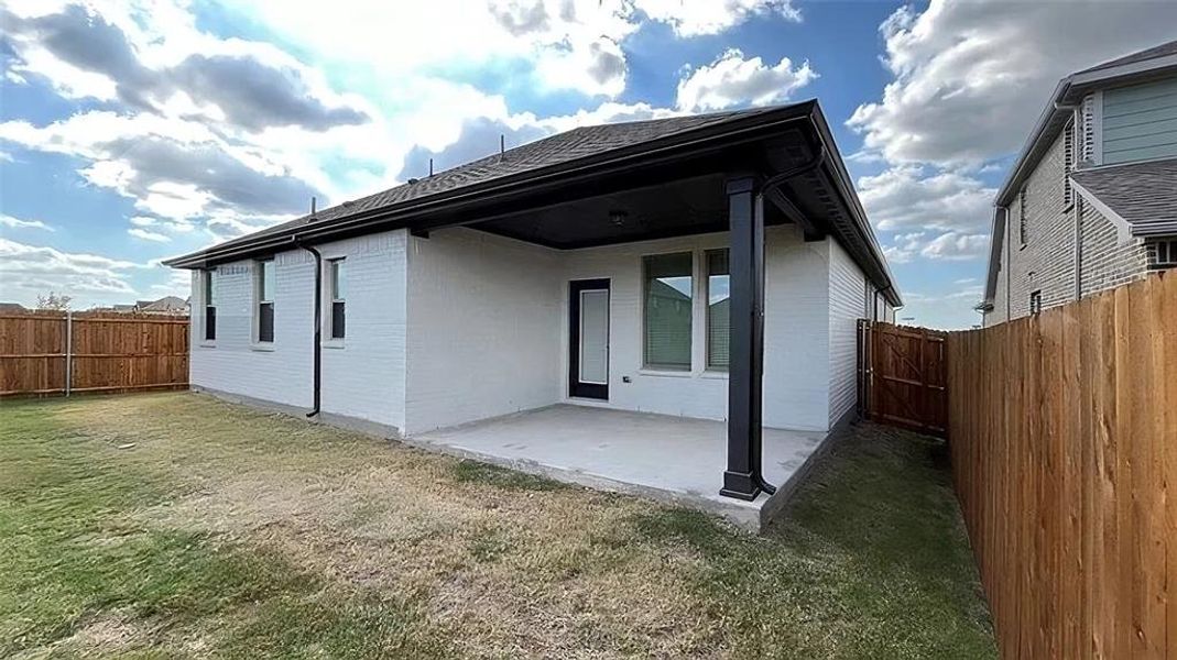 Rear view of house featuring a patio area, a fenced backyard, brick siding, and a gate