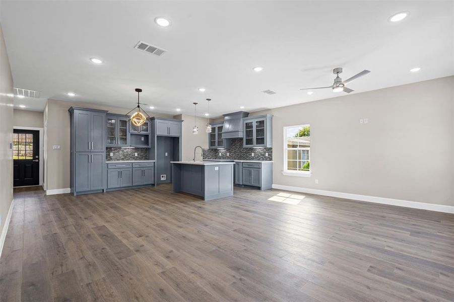 Kitchen featuring glass insert cabinets, open floor plan, gray cabinetry, hanging light fixtures, and recessed lighting Kitchen featuring glass insert cabinets, open floor plan, gray cabinetry, hanging light fixtures, and recessed lighting