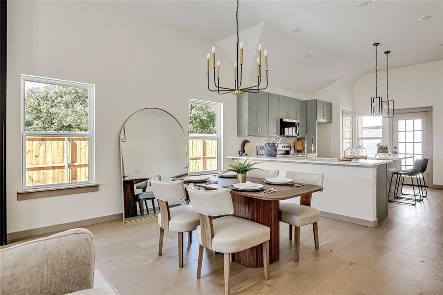 Dining area with a chandelier, light wood-style floors, and high vaulted ceiling